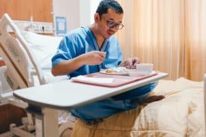A man is having a nutrient-rich lunch while sitting on his hospital bed after surgery.
