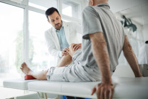 Senior man having his knee examined by a doctor